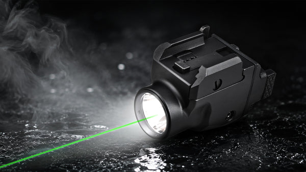 A tactical black flashlight emitting a bright green laser beam across a dark, wet surface with visible mist and reflections.
