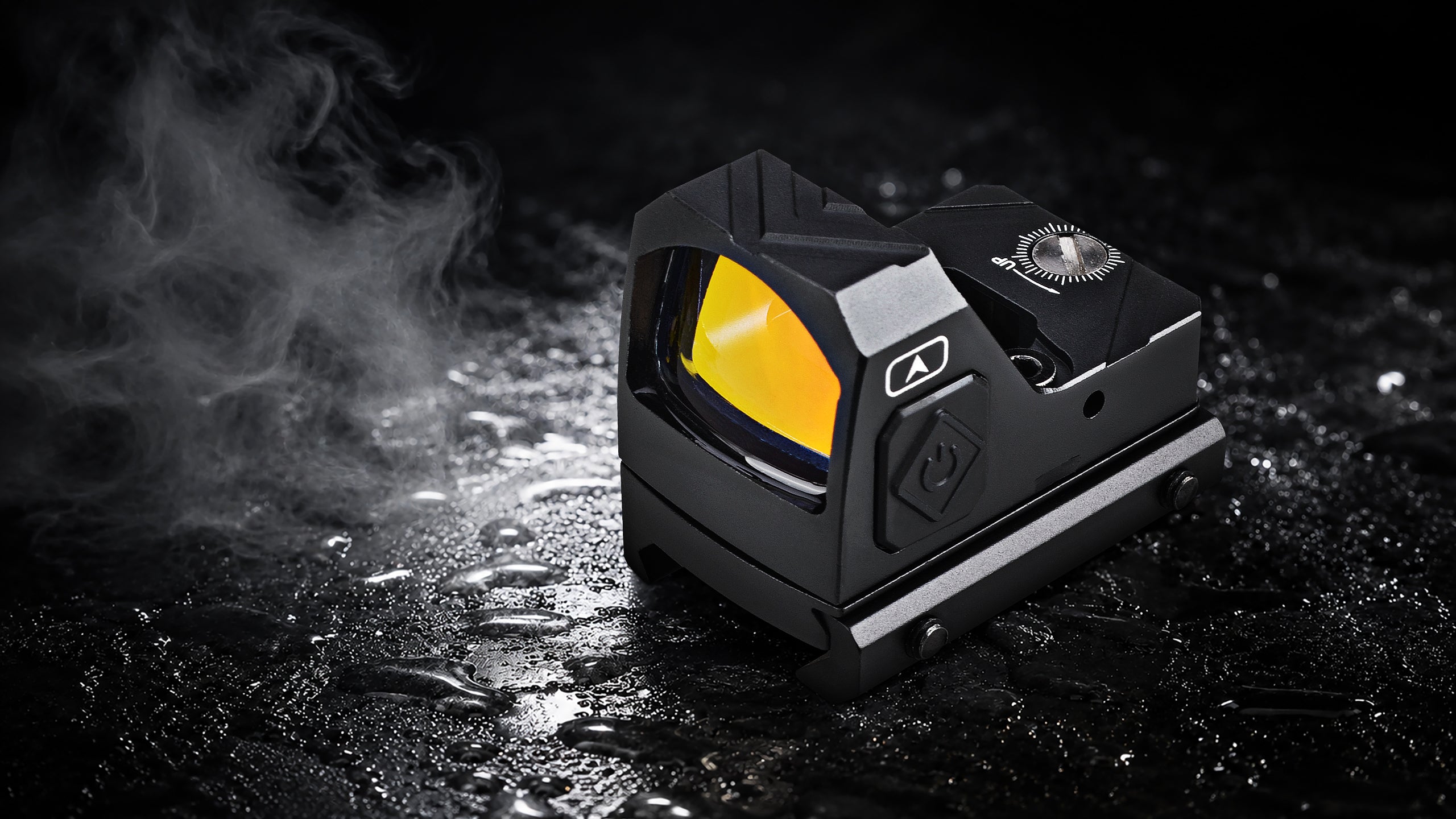A black tactical red dot sight with a bright yellow lens, shown on a wet dark surface with steam or smoke on the left.